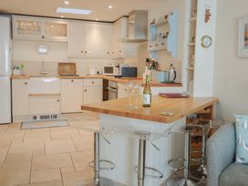A kitchen with cabinets, sink, and bar stools at Phoenix Cottage in Lyme Regis