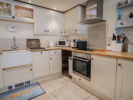 A kitchen with cabinets, a sink, and appliances at Phoenix Cottage in Lyme Regis