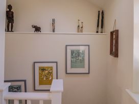 A staircase with wooden decor and framed artworks at Phoenix Cottage in Lyme Regis