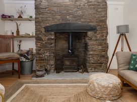 A living room with a stone fireplace and a wood stove at Bedford Cottage in Yelverton