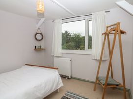 A bedroom with a bed, window, and a clothing rack at Bedford Cottage in Yelverton