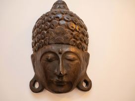 A wooden Buddha head sculpture on a wall at Apartment 12