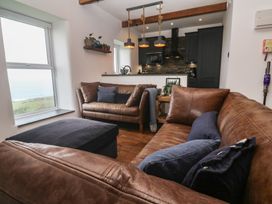 A living room with a sofa and kitchen area at Cape View Cape Cornwall near St Just