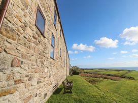 A stone wall with windows and a bench overlooking the sea at Cape View Cape Cornwall near St Just