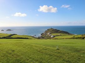 A coastal view with green fields and a lighthouse at Cape View in Cape Cornwall near St Just