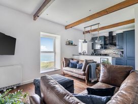 A living room with a television, window and kitchen at Cape View near St Just