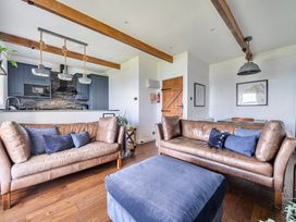 A living room with sofas and a kitchen area at Cape View near St Just