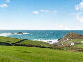 A view of the ocean and cliff with houses and a lighthouse at Cape View near Cape Cornwall