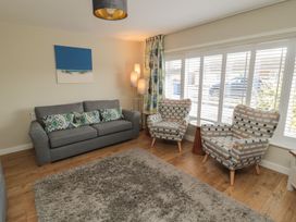 A living room with a sofa, armchairs, and a lamp at 7 Longstone Close Chathill