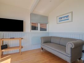 A living room with a sofa and television at Salt & Stone Lyme Regis