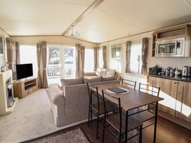 A living room with a television and dining table at 23 Gull Court in Porthmadog