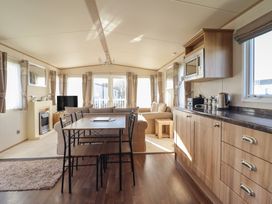 A living room with a sofa and dining area at 23 Gull Court Porthmadog