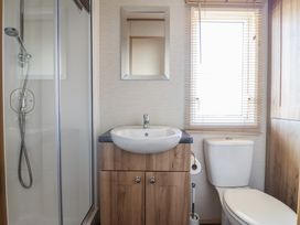 A bathroom with a shower, sink, and toilet at 23 Gull Court in Porthmadog