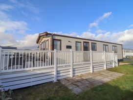 A mobile home with a deck and fence at 23 Gull Court in Porthmadog