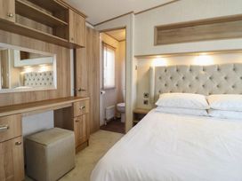 A bedroom with a bed and vanity area at 23 Gull Court in Porthmadog