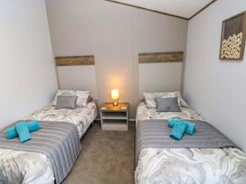 A bedroom with two beds and a bedside table at Dukes Meadow, Carmarthen