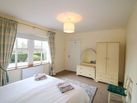 A bedroom with a bed, wardrobe, and window at Lugdine Lodge in Glengarriff