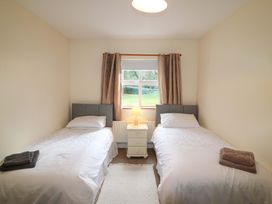 A bedroom with two beds and a lamp at Lugdine Lodge in Glengarriff