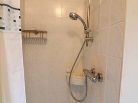 A shower with a curtain and showerhead at Lugdine Lodge in Glengarriff