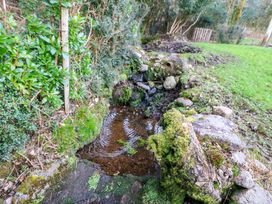 A stream flowing over rocks surrounded by grass and bushes at Lugdine Lodge in Glengarriff