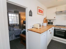 A kitchen with appliances and a view of a living room at Burnside Cottage in Grange-Over-Sands