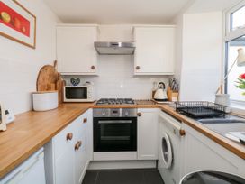 A kitchen with stove, oven, sink, and washing machine at Burnside Cottage in Grange-Over-Sands