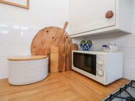 A kitchen counter with a microwave and cutting boards at Burnside Cottage in Grange-Over-Sands