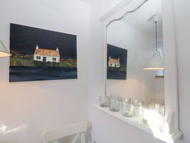 A dining room with a painting and mirror at Burnside Cottage in Grange-Over-Sands