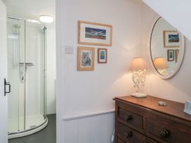 A bathroom with a shower, dresser and wall art at Burnside Cottage in Grange-Over-Sands