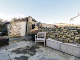 A patio with a stone wall, shed and seating at Burnside Cottage in Grange-Over-Sands
