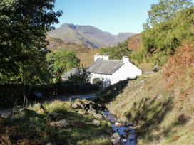 A cottage near a stream surrounded by trees at Burnside Cottage in Grange-Over-Sands