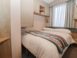 A bedroom with a bed covered by a blanket at Lodge 22, Moselle in Malton