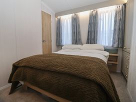 A bedroom with a bed and large window at Lodge 22, Moselle Malton