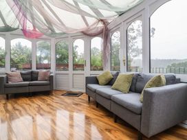A conservatory with sofas and large windows at West Down Country House in South Molton