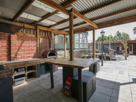 An outdoor kitchen with wooden table and pizza oven at West Down Country House in South Molton