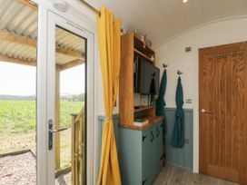 An entryway with a tv and a door at Daisy Shepherd's Hut in South Molton