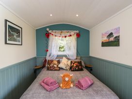 A bedroom with a bed and decorative items at Daisy Shepherd's Hut in South Molton