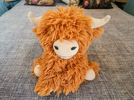 A plush toy in the shape of a cow on a bed at Daisy Shepherd's Hut in South Molton