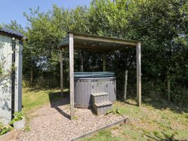 A hot tub under a shelter in an outdoor area at Daisy Shepherd's Hut South Molton