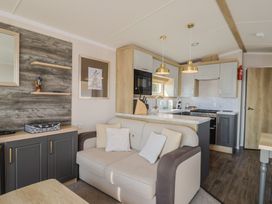 A living room with a sofa and kitchen appliances at Bordeaux in Ladram Bay Otterton