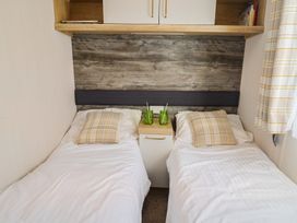 A bedroom with two beds and a bedside table at Bordeaux Ladram Bay Otterton
