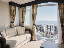 A living room with a sofa and a view of the sea at Bordeaux in Ladram Bay Otterton