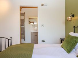 A bedroom with a bed and an ensuite bathroom at Nelli Lodge at Mile End Crediton