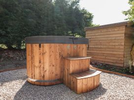 A hot tub with steps next to a wooden shed at Nelli Lodge at Mile End Crediton