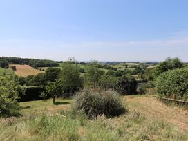 A garden with grass and trees overlooking hills at Nelli Lodge at Mile End, Crediton