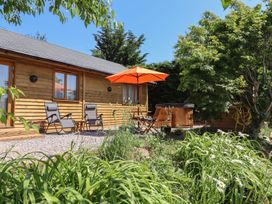 An outdoor patio with deck chairs and a hot tub at Nelli Lodge at Mile End, Crediton