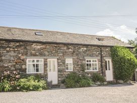 A stone cottage with windows and garden plants at Cottage 1 in Braithwaite