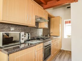 A kitchen with cabinets, a microwave, kettle, and stove at Cottage 1 in Braithwaite
