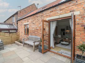 An outdoor patio with seating and a view into the living area at Bumble Bee Lodge in Filey