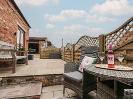 A patio with chairs and a table featuring wine glasses at Bumble Bee Lodge in Filey